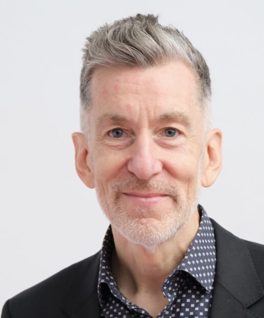A headshot of Andrew Davies against a neutral grey background