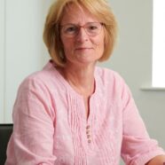 Jo Hanlon sitting down at a desk, smiling at a camera.