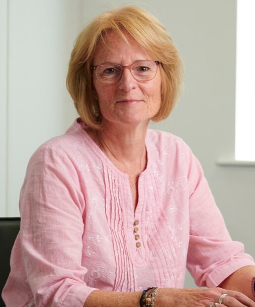 Jo Hanlon sitting down at a desk, smiling at a camera.