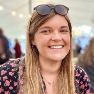 Rachael McDonald is smiling at the camera. She is sat outside, with sunglasses on her head.