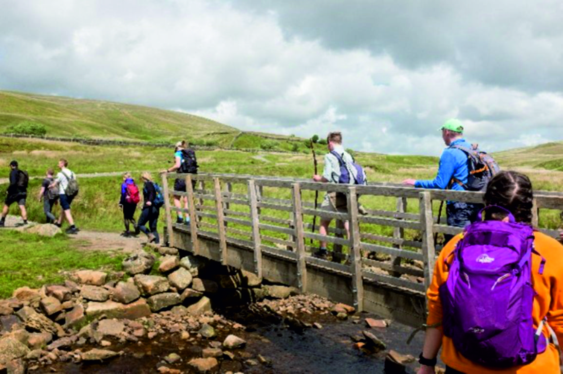 An image of nine YHEC staff crossing a bridge on the Yorkshire Three Peaks walk