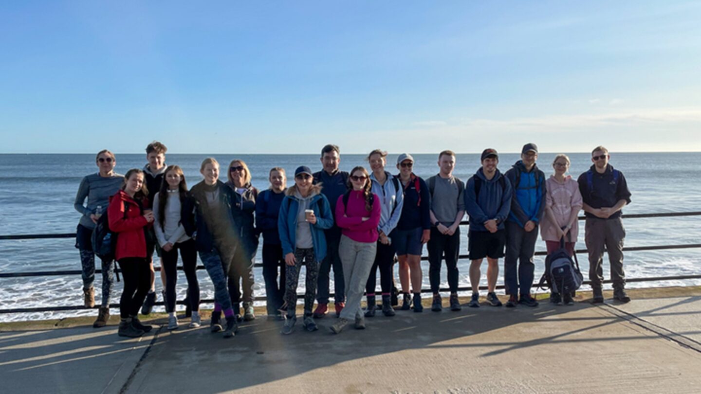 An image of 17 YHEC staff standing in front of the sea, who participated in the Scarborough to Whitby walk